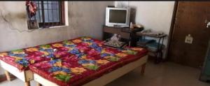 a bedroom with a bed and a desk with a television at Agnihotri Tourism Centre in Machhrehta
