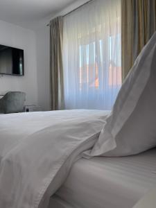 a white bed with a pillow and a window at Anda Rooms in Orşova