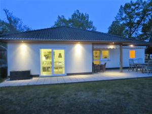 a small white house with a patio at night at Ferienhaus Schillo in Rangsdorf