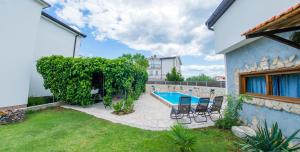 a backyard with a pool and chairs and a house at Estate - Villa Discovery in Ljubuški