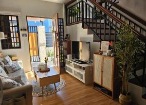 a living room with a staircase with a couch and a tv at CASA CORAZON Spacious 4BR House Near Tagaytay for Wedding Prep Family Gatherings Reunions and Celebrations Pet Friendly and PWD Accessible in Dagatan