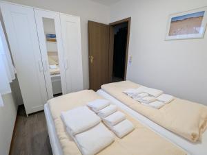 a white room with two beds with towels on them at Haus Ekke Nekkepenn I, Whg 5 in Wyk auf Föhr