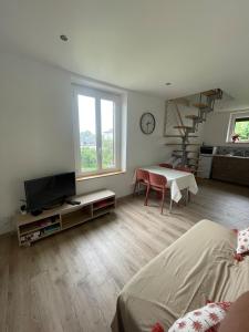 ein Wohnzimmer mit einem Bett, einem TV und einer Treppe in der Unterkunft Bienvenue au petit point de vue in Lisieux