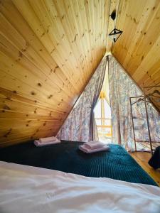 a bed in a wooden room with a large window at Borjomi Story in Borjomi