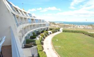 a view of a building with a lawn and the ocean at La Lagune in Le Grau-du-Roi