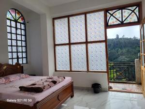 a bedroom with a bed and windows with a view at Bison Valley View Stay in Kodaikānāl