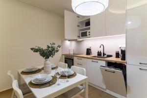 a kitchen with white cabinets and a white table and chairs at Elea in Mytilene