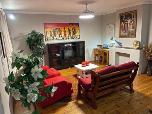 a living room with a red couch and a fireplace at The Tranquil Golden Retreat in Johannesburg