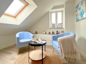 a attic living room with two blue chairs and a table at Studio spacieux et élégant au cœur de Bourbourg - gare à proximité in Bourbourg