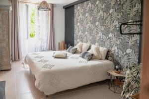 a bedroom with a white bed with a patterned wall at Ô Vieux Moulin in Duras