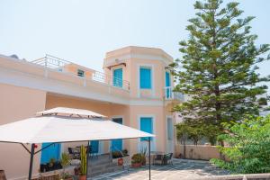 een groot gebouw met een paraplu en een boom bij 1944-Heritage House in Lardos