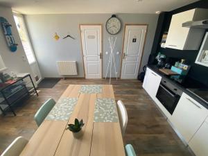 eine Küche mit einem Holztisch mit Stühlen und einer Uhr an der Wand in der Unterkunft Petite maison de campagne in Sainte-Croix-sur-Mer