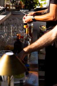 a man standing in a kitchen with bottles of alcohol at Hotel Puerta del Mar - Adults Recommended in Nerja