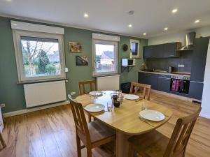 a dining room with a wooden table and a kitchen at Sali Homes -Business Stay-Rheinische Gemütlichkeit in Kleve