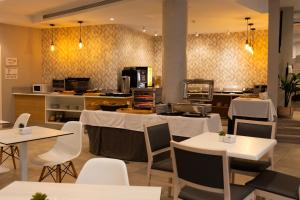 a restaurant with white tables and chairs and a kitchen at Hotel Puerta del Mar - Adults Recommended in Nerja