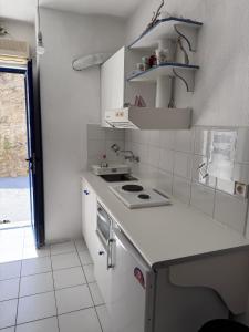 a white kitchen with a stove and a sink at Evangelos Politis Rooms Kea in Pisses