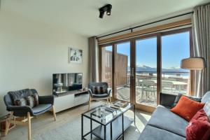 a living room with a couch and a tv at ARC 1600, LE RIDGE, Appartement 06 personnes Duplex Vue Montagne - ski aux pieds - Sauna, Hammam, Piscine, Salle de sport-fitness in Arc 1600