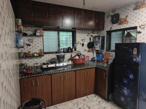 a kitchen with wooden cabinets and a black refrigerator at Shafi Villa in Neral