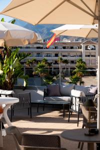 a patio with a couch and tables and umbrellas at Hotel Puerta del Mar - Adults Recommended in Nerja