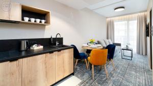 シュクラルスカ・ポレンバにあるApartamenty Good Time - Zloty Horyzont Resort- Bliżej Chmurのテーブルと椅子のあるキッチンとリビングルーム