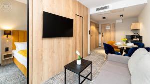 シュクラルスカ・ポレンバにあるApartamenty Good Time - Zloty Horyzont Resort- Bliżej Chmurのソファとテレビが壁に付いたホテルルーム