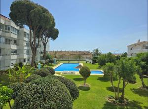 a garden with a swimming pool and trees and a building at APARTAMENTO Los CISNES in Benalmádena