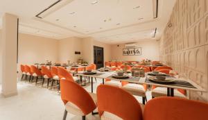 a dining room with orange chairs and tables at Flare By Blaze in Bhopal