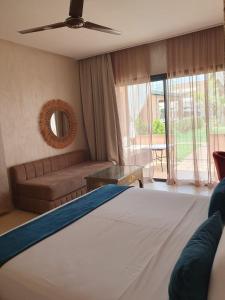 a bedroom with a bed and a couch and a window at Hôtel Jardins de lina et lea in Marrakech +30 photos