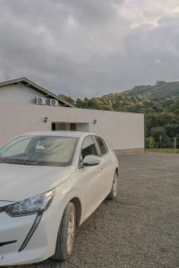a white car parked in a parking lot at Hotel e hospedagem Alma de Campo in Rio Rufino
