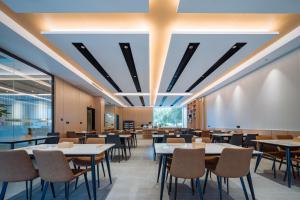 uma sala de jantar com mesas, cadeiras e janelas em Parker Hotel Huangshan Tunxi Old Street Branch em Montanhas Huangshan