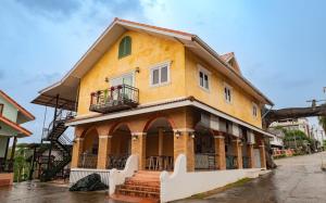 a yellow building with a balcony on a street at Samprasob Resort in Sangkhla Buri