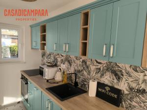 a kitchen with blue cabinets and a counter with a microwave at Casa di Campara Villa in Neum
