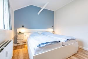 een witte slaapkamer met een bed met blauwe muren bij Steger-Hüs Wohnung 37 in Rantum