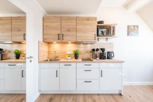a kitchen with white cabinets and wooden walls at Steger-Hüs Wohnung 41 in Rantum +12 photos