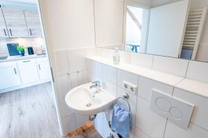 a white bathroom with a sink and a mirror at Steger-Hüs Wohnung 42 in Rantum