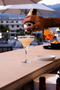 a person pouring a drink into a martini glass at Hotel Puerta del Mar - Adults Recommended in Nerja