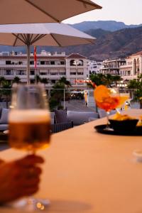 a person holding a glass of beer on a table at Hotel Puerta del Mar - Adults Recommended in Nerja