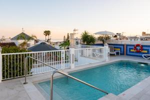 a swimming pool with a white fence and the ocean at Hotel Puerta del Mar - Adults Recommended in Nerja