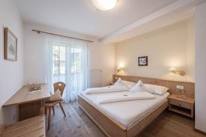 a bedroom with a large bed and a desk at Tirolerhof - panoramic apartments in Natz-Schabs