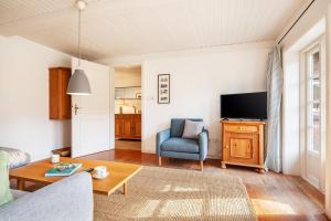 a living room with a blue chair and a tv at Letj Lindguard in Alkersum