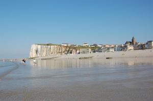 a beach with a group of people walking in the water at Chambres 1 a 4 personnes CAPRICES ENSOLEILLES 300 m plage avec vue 2 chambres in Mers-les-Bains