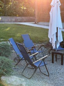 two lawn chairs and an umbrella in a yard at Шале Рутенія - Chalet Rutenia apartments in Neporotovo