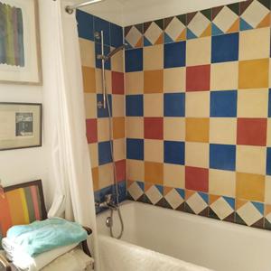 a bathroom with a tub and a colorful tile wall at 2 Rue de la Tour in Aniane