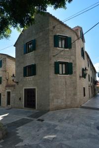 un gran edificio de piedra con ventanas con contraventanas verdes en Villa Desideria en Split