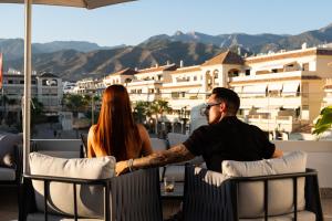 a man and a woman sitting at a table on a balcony at Hotel Puerta del Mar - Adults Recommended in Nerja