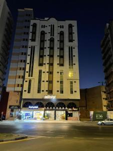 a tall building with a parking lot in front of it at فندق منارة البيت in An Naqāʼ