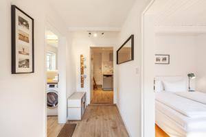 a white bedroom with a bed and a hallway at Kurnkoomer in Alkersum +10 photos