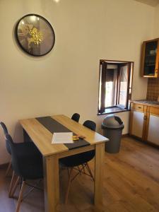 a dining room table with chairs and a clock on the wall at Appartement entier - cosy et lumineux - Plein centre-ville in Épinal