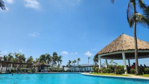 a pool at a resort with palm trees and a thatch roof at Casa 3 recamaras con alberca compartida Acapulco diamante in General Juan N Alvarez International Airport