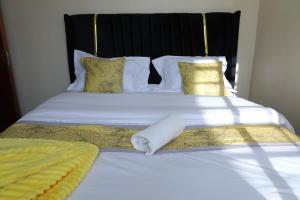 a bed with white sheets and yellow pillows at Naivasha Lake Vista Guesthouse in Lotus Island